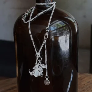 Datura Flower Necklace-Handmade S925 Silver With Custom Disc 03 Handmade S925 Silver Necklace with detailed datura flower pendant and custom disc tag engraved “Tsubasa 925”; a botanical-inspired Flower Necklace draped around a dark glass bottle, highlighting silver craftsmanship and contrast.