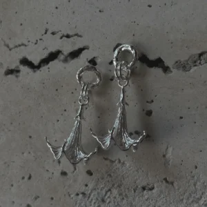 Datura-Handcrafted S925 Sterling Silver Flower Earrings 02 S925 Sterling Silver Datura Flower Earrings with sculptural petal-like curves and organic detailing; handcrafted Silver Earrings styled against cracked concrete for contrast and elegance.