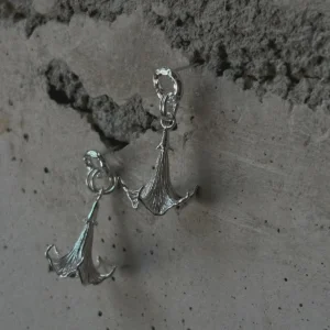 S925 Sterling Silver Datura Flower Earrings with sculptural, downward-facing blooms and textured petal details; handcrafted Silver Earrings styled against a rough concrete wall for contrast and elegance.