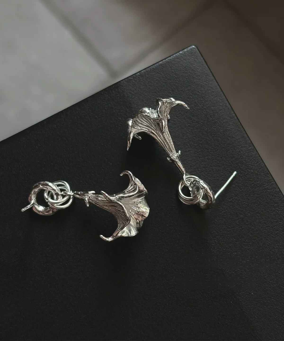 Datura-Handcrafted S925 Sterling Silver Flower Earrings 08 S925 Sterling Silver Flower Earrings with trumpet-shaped floral design and twisted knot detail; handcrafted Silver Earrings featuring botanical textures and sculptural elegance, styled on black background.