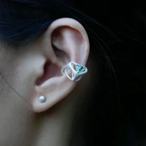 Close-up of ear wearing Dreamscape Garden S925 Silver Ear Cuff with green triangular gemstone and sculptural silver framework; a modern Silver Ear Cuff blending geometric elegance with botanical inspiration.