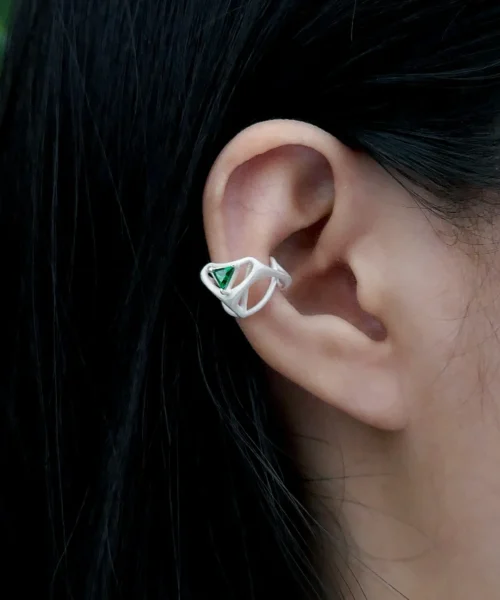 Close-up of ear wearing Dreamscape Garden S925 Silver Ear Cuff with green triangular gemstone and sculptural silver design; a botanical-inspired Silver Ear Cuff blending geometric elegance and modern craftsmanship.
