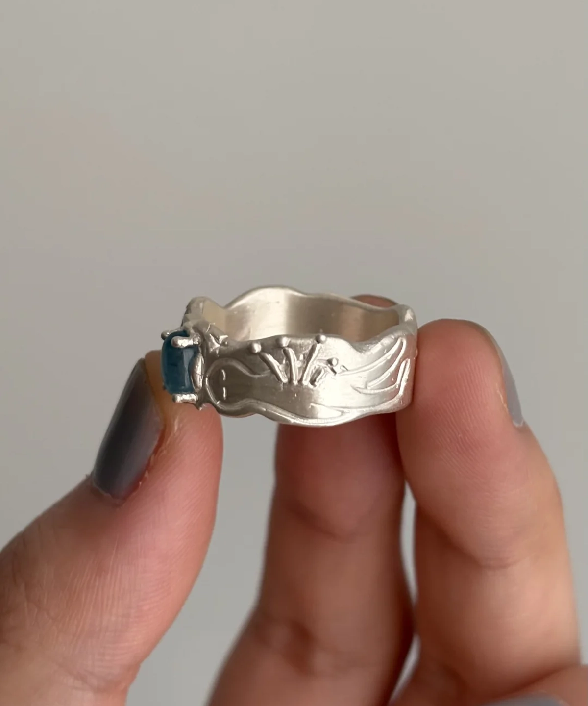 Hand holding a Handmade 999 Silver Ring with rectangular Aquamarine gemstone, engraved wing and dot motifs; a poetic Aquamarine Ring crafted in fine silver, celebrating March birthstone elegance and artisan detail.