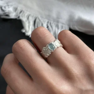 Close-up of a hand wearing a Handmade 999 Silver Ring with a light blue Aquamarine gemstone and engraved band details; a poetic Aquamarine Ring crafted in fine silver, celebrating March birthstone elegance and artisan craftsmanship.