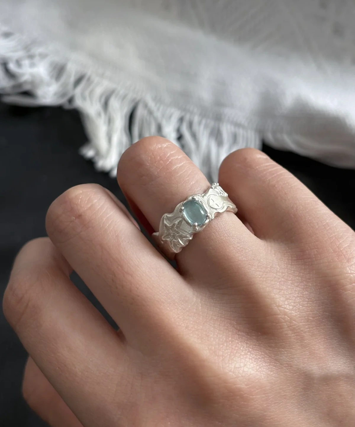 Close-up of a hand wearing a Handmade 999 Silver Ring with a light blue Aquamarine gemstone and engraved band details; a poetic Aquamarine Ring crafted in fine silver, celebrating March birthstone elegance and artisan craftsmanship.