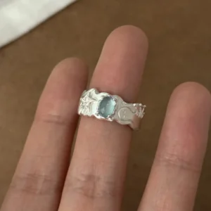 Close-up of a hand wearing a Handmade 999 Silver Ring with oval Aquamarine gemstone, featuring starfish, crescent moon, and wave motifs; a poetic Aquamarine Ring crafted in fine silver, celebrating March birthstone elegance and ocean-inspired artistry.