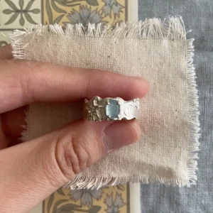 Hand holding a Handmade 999 Silver Ring with light blue Aquamarine gemstone, engraved star and circular motifs; a poetic Aquamarine Ring crafted in fine silver, celebrating March birthstone elegance and artisan detail.