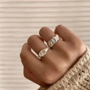 Close-up of a hand wearing two silver rings, one with a rectangular Aquamarine gemstone and one with an abstract coral-like design; Handmade 999 Silver Ring showcasing artistic texture and celebrating the March birthstone with Aquamarine Ring elegance.