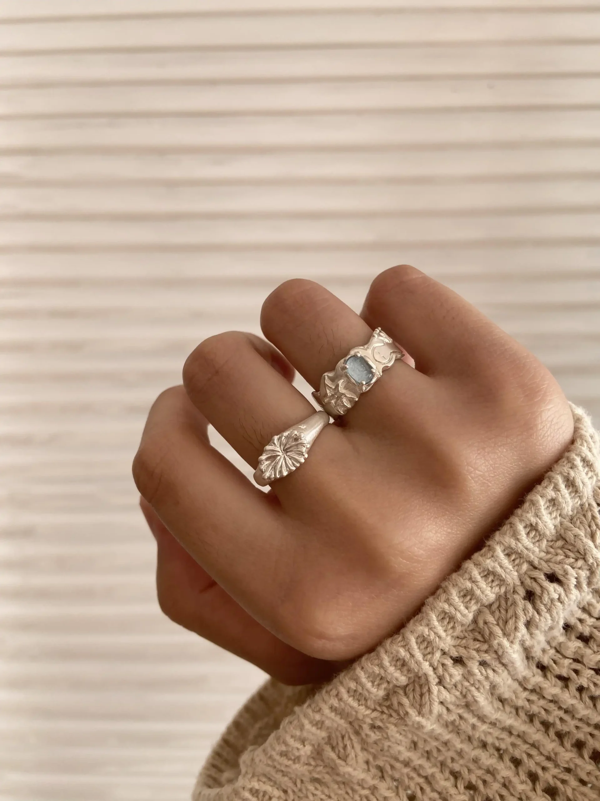 Close-up of a hand wearing two silver rings, one with a rectangular Aquamarine gemstone and one with an abstract coral-like design; Handmade 999 Silver Ring showcasing artistic texture and celebrating the March birthstone with Aquamarine Ring elegance.