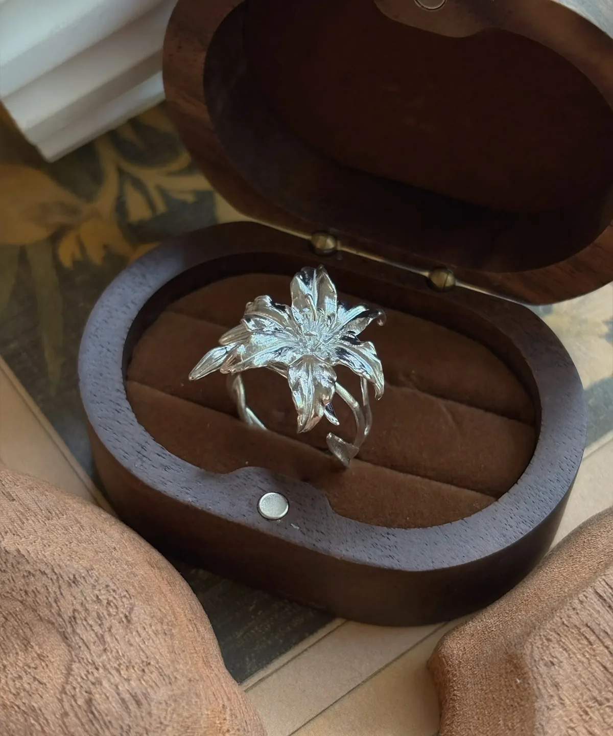 Handmade S925 Sterling Silver Lily Ring 04 Handmade S925 Sterling Silver Lily Ring with sculpted petals and lifelike floral textures, placed in an open wooden box with soft brown interior; a botanical Silver Ring inspired by the elegance of the lily flower.