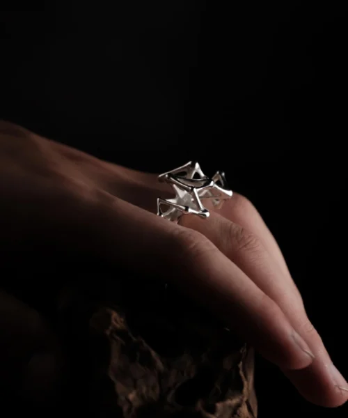 Leaping Orbit Handcrafted 999 Fine Silver Statement Ring with angular geometric design, worn on hand; a sculptural Silver Statement Ring featuring polished interconnected shapes, styled against a textured organic surface.