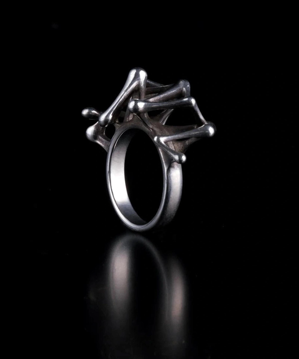 Leaping Orbit Handcrafted 999 Fine Silver Statement Ring with sculptural geometric top design; a bold Silver Statement Ring featuring interconnected rods and rounded ends, styled against a black background for dramatic contrast.