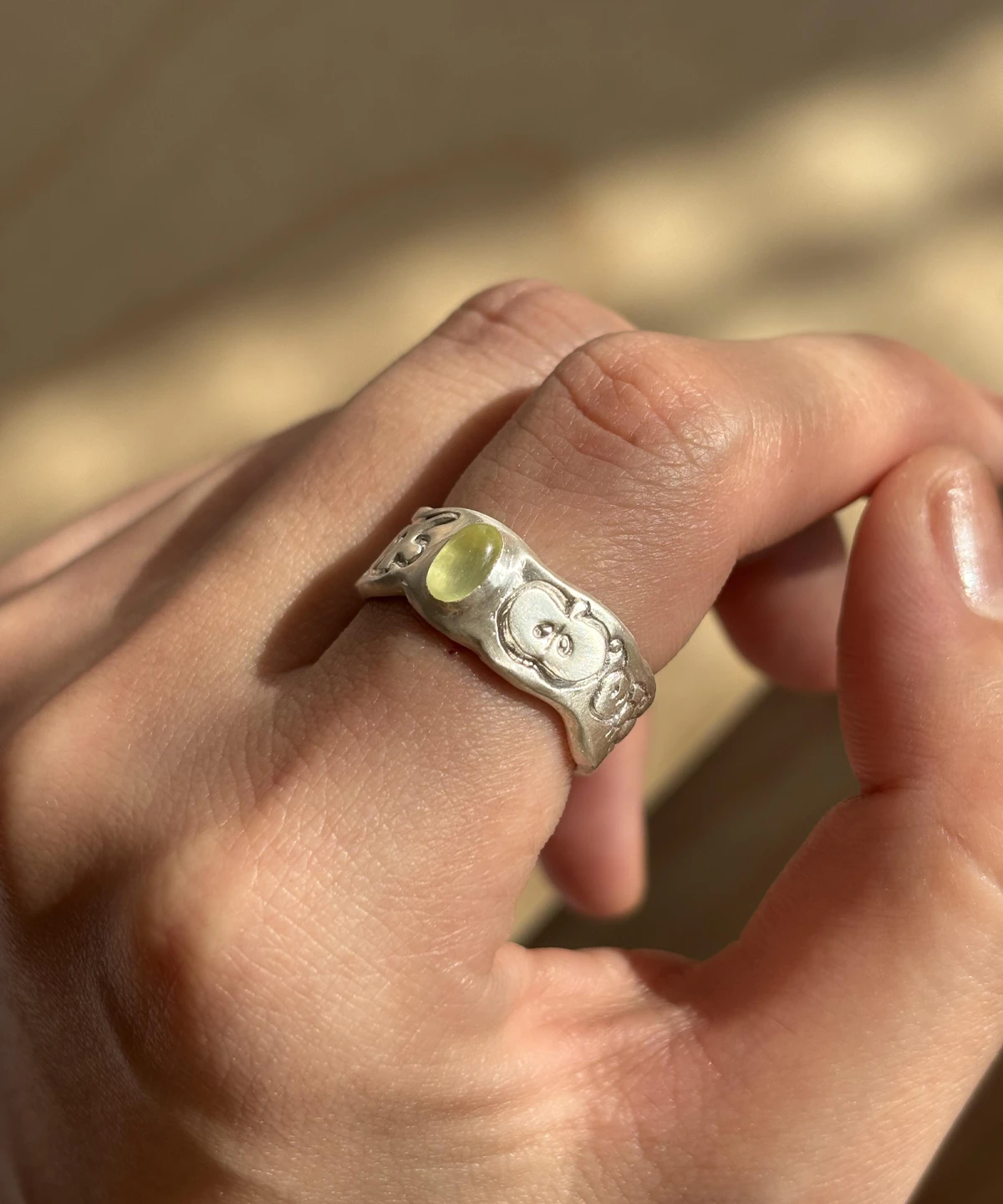 Natural Peridot Ring in 999 Silver with translucent yellow-green gemstone and embossed apple motifs; a handcrafted 999 Silver Ring featuring organic textures and symbolic fruit-inspired design, worn on hand in close-up view.