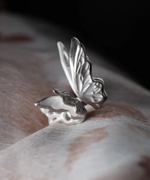 Close-up of a handcrafted S925 Sterling Silver Butterfly Ring with etched wing details, resting on soft fabric; elegant Silver Ring design showcasing delicate craftsmanship and nature-inspired beauty in a sculptural Butterfly Ring form.