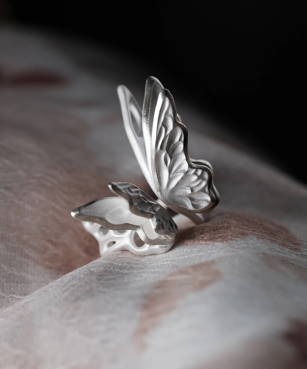 Close-up of a handcrafted S925 Sterling Silver Butterfly Ring with etched wing details, resting on soft fabric; elegant Silver Ring design showcasing delicate craftsmanship and nature-inspired beauty in a sculptural Butterfly Ring form.
