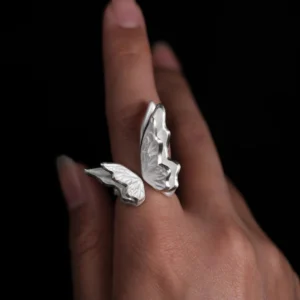 Close-up of a hand wearing a S925 Sterling Silver Butterfly Ring with sculptural open-wing design and lifelike texture, set against a black background; elegant Silver Ring showcasing handcrafted detail and nature-inspired Butterfly Ring artistry.