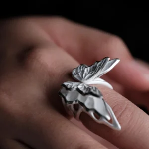Close-up of a hand wearing a S925 Sterling Silver Butterfly Ring with sculptural wings and lifelike texture, set against a dark background; elegant Silver Ring design showcasing handcrafted detail and nature-inspired Butterfly Ring artistry.