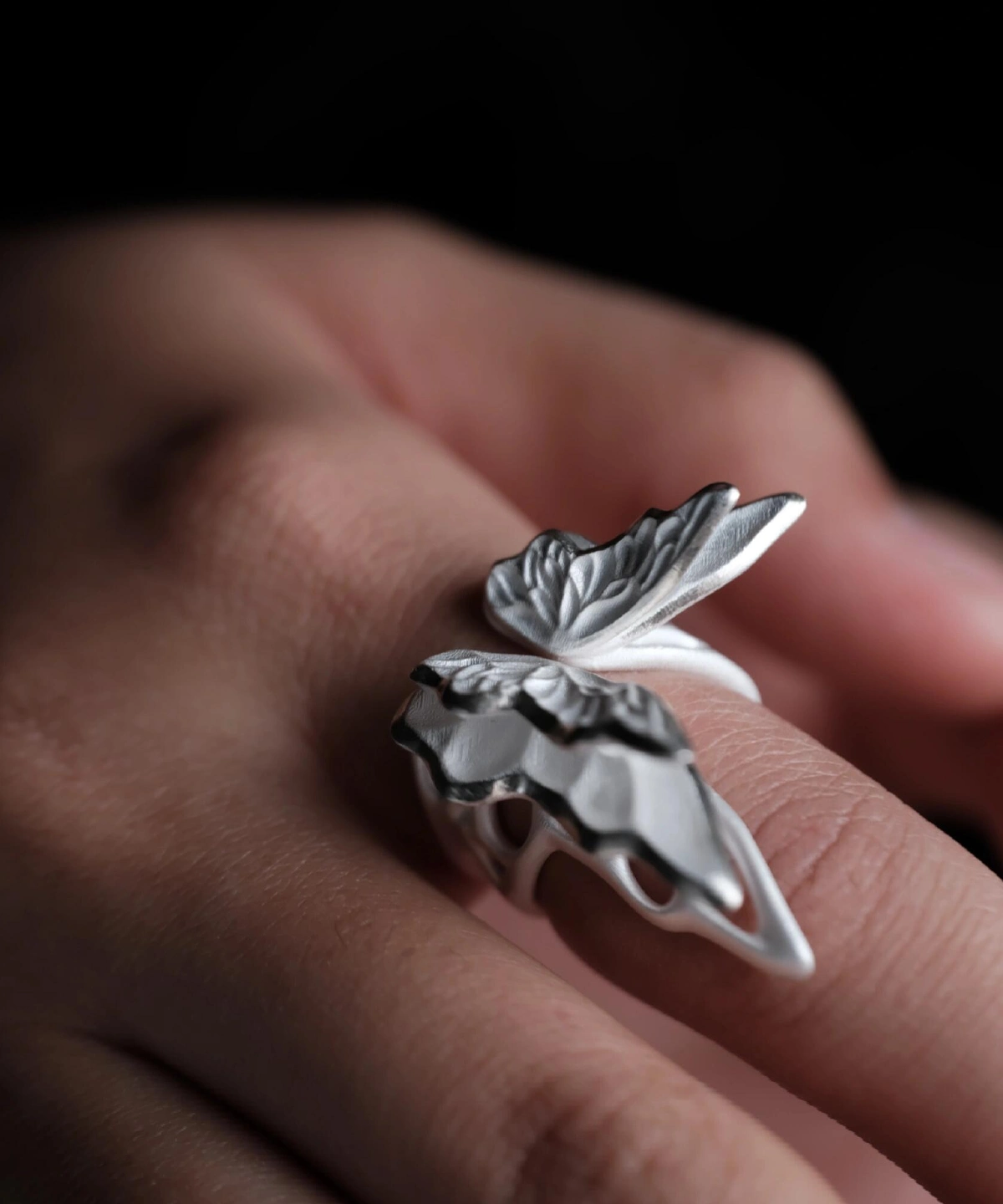 Close-up of a hand wearing a S925 Sterling Silver Butterfly Ring with sculptural wings and lifelike texture, set against a dark background; elegant Silver Ring design showcasing handcrafted detail and nature-inspired Butterfly Ring artistry.