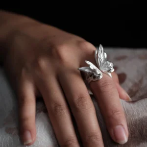Close-up of a hand wearing a S925 Sterling Silver Butterfly Ring with sculptural wings and lifelike texture, set against a dark background; elegant Silver Ring design showcasing handcrafted Butterfly Ring artistry and nature-inspired elegance.