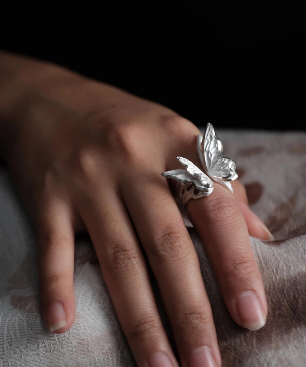 Close-up of a hand wearing a S925 Sterling Silver Butterfly Ring with sculptural wings and lifelike texture, set against a dark background; elegant Silver Ring design showcasing handcrafted Butterfly Ring artistry and nature-inspired elegance.