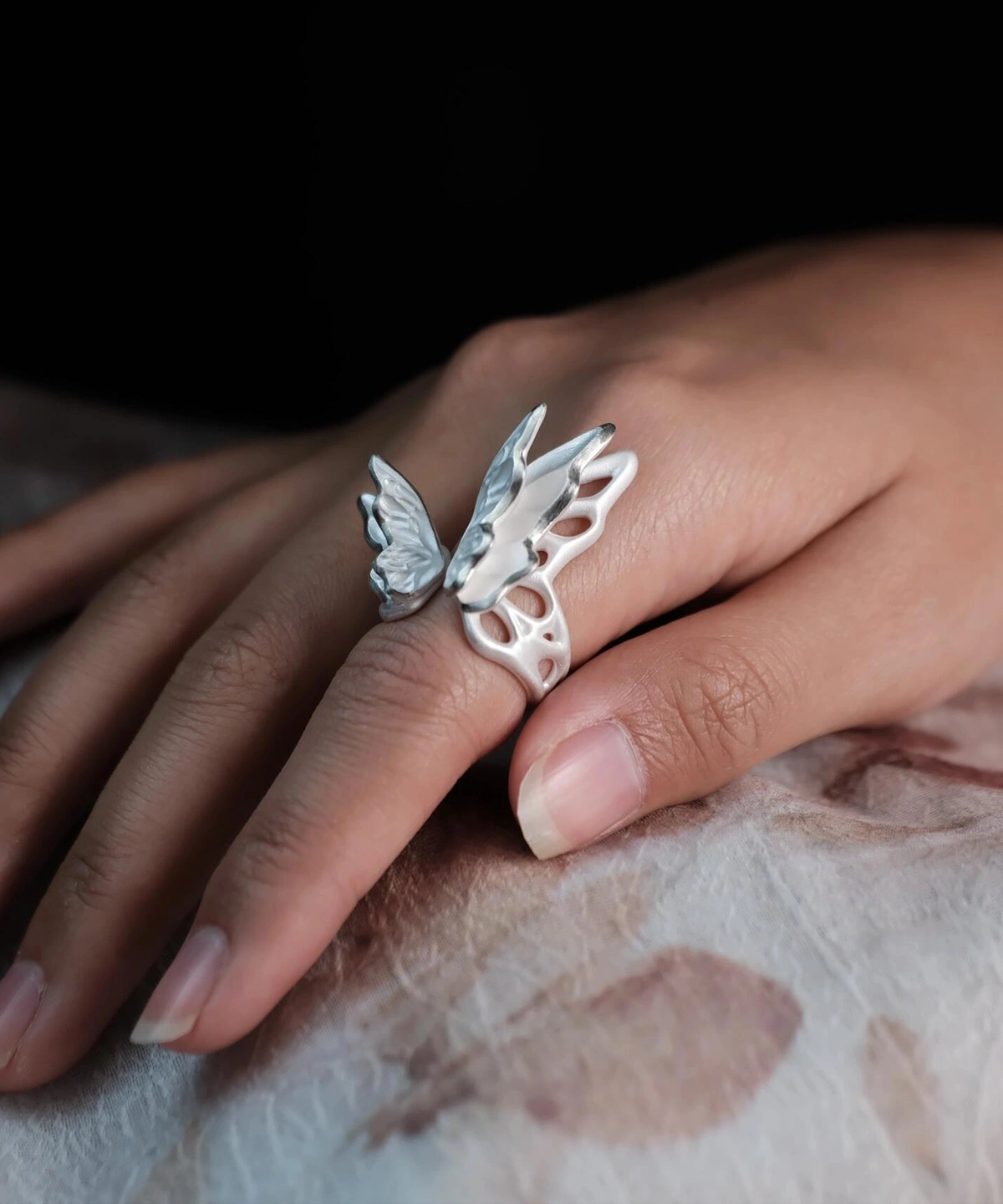 Close-up of a hand wearing a S925 Sterling Silver Butterfly Ring with sculptural open wings and lifelike texture, set against a dark background; elegant Silver Ring showcasing handcrafted Butterfly Ring artistry and nature-inspired design.