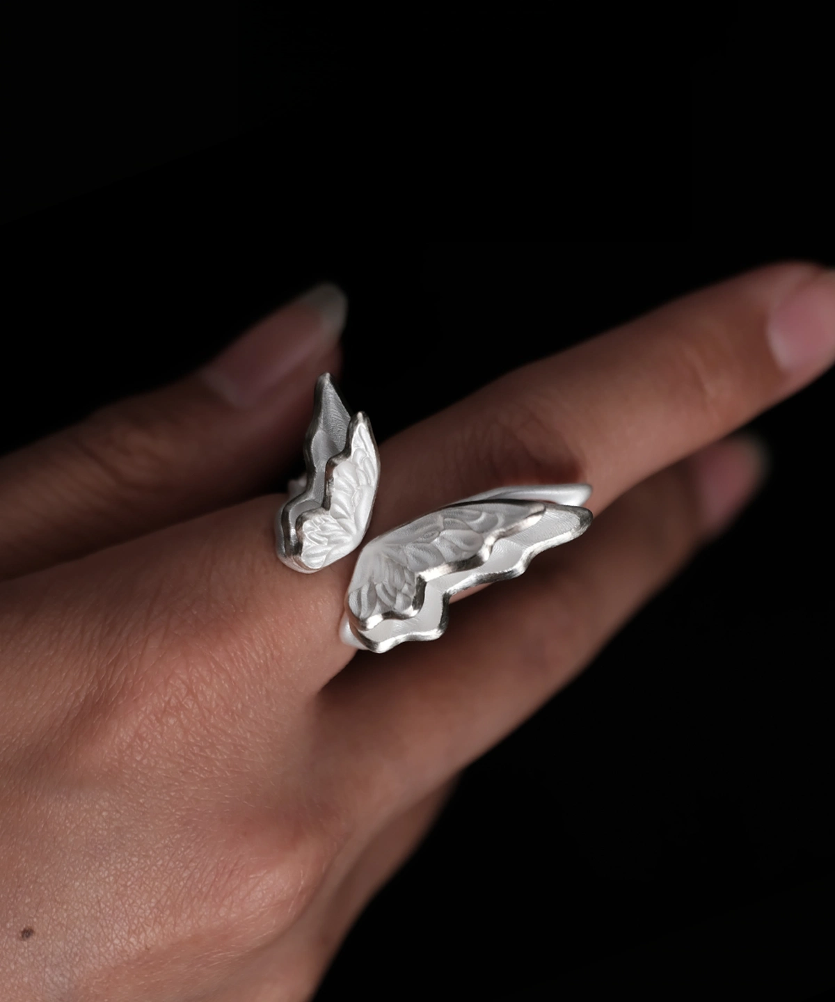 Close-up of a hand wearing a S925 Sterling Silver Butterfly Ring with sculptural open wings and lifelike texture, set against a dark background; elegant Silver Ring showcasing handcrafted Butterfly Ring artistry and nature-inspired design.