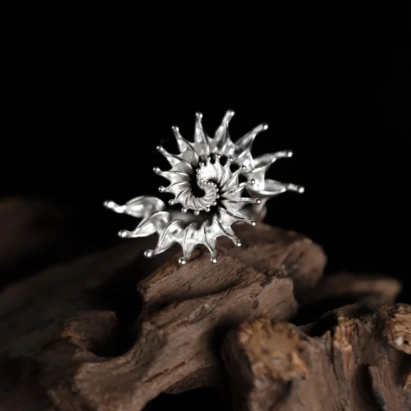 S925 Sterling Silver Spiral Ring Jewelry with radiating petal-like extensions in a fractal-inspired sunburst design, placed on driftwood against a black background; bold Statement Ring showcasing sculptural elegance and intricate Silver Ring craftsmanship.