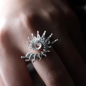 Close-up of a hand wearing a S925 Sterling Silver Spiral Ring Jewelry with radiating petal-like extensions in a stylized sunburst design; bold Statement Ring showcasing intricate craftsmanship and sculptural Silver Ring elegance.