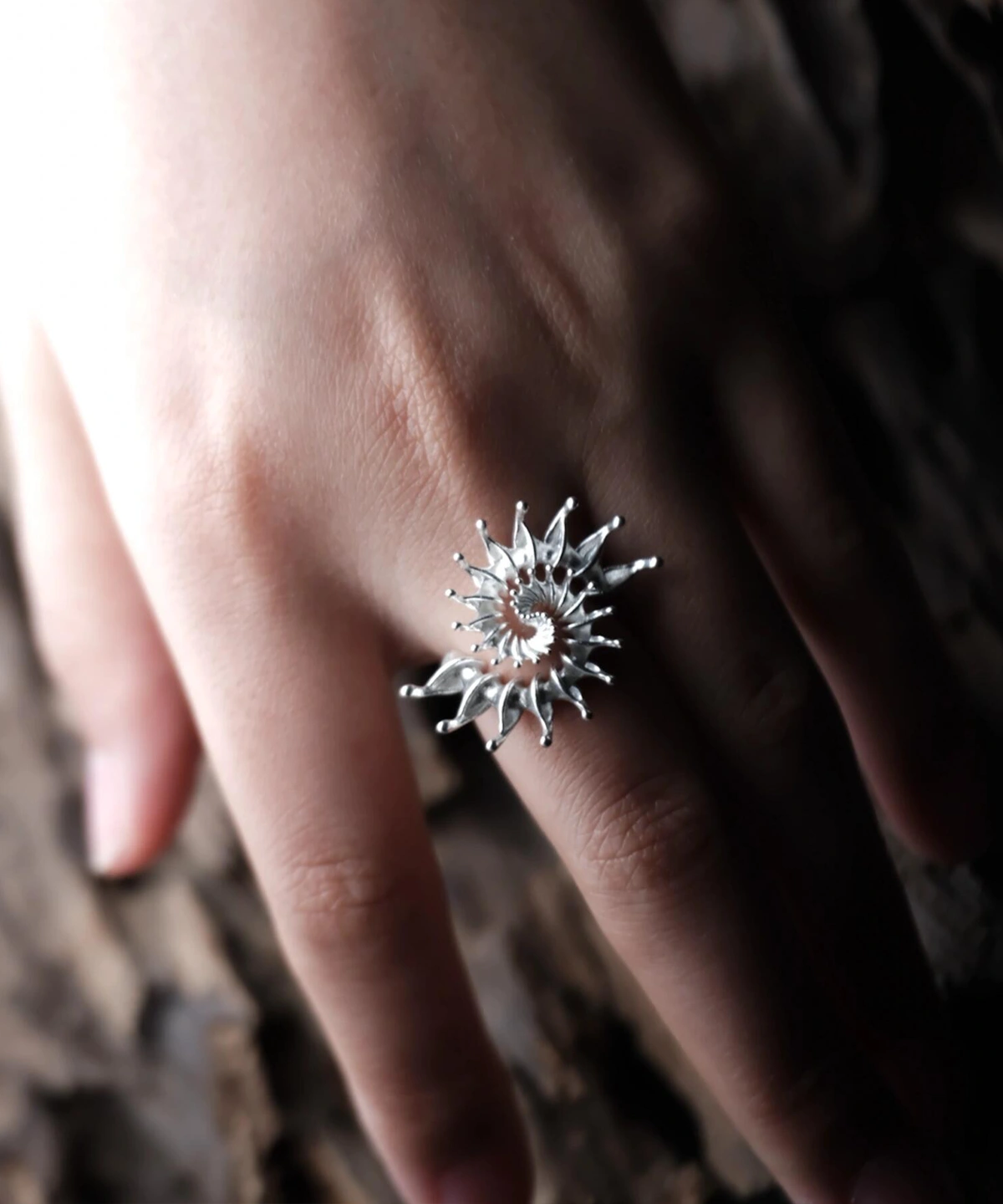 S925 Sterling Silver Spiral Ring Jewelry-Handmade Artistic Statement Ring 07 Close-up of a hand wearing a S925 Sterling Silver Spiral Ring Jewelry with radiating petal-like spikes in a sunburst design, set against a natural textured background; bold Statement Ring showcasing artistic craftsmanship and sculptural Silver Ring elegance.