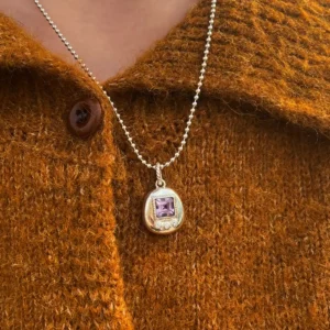 Tamagotchi Necklace with light purple square gemstone and three clear accent stones in S925 silver; worn over brownish-orange knit sweater with buttons, showcasing Pet Necklace elegance.