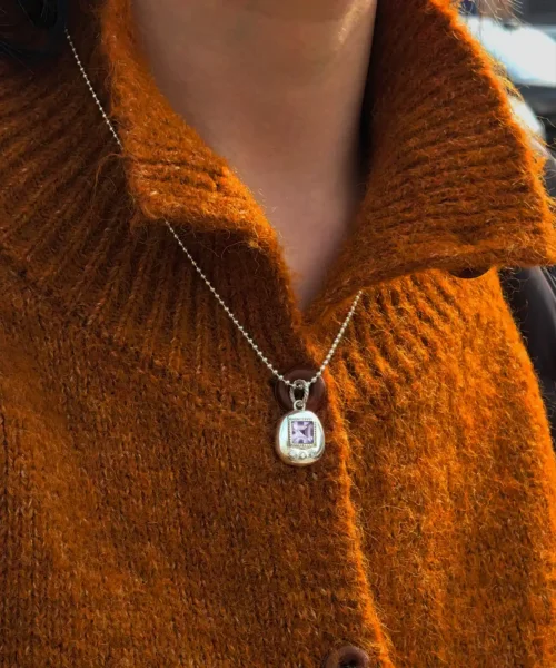 Tamagotchi Necklace with light purple square gemstone and three clear accent stones in S925 silver; worn over rust-colored sweater, showcasing Pet Necklace craftsmanship and nostalgic elegance.