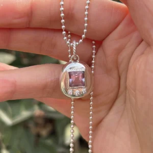 Custom Handmade S925 Sterling Silver Tamagotchi Necklace 09 Tamagotchi Necklace with light purple square gemstone and three clear accent stones in S925 silver; held by hand outdoors with green background, showcasing Pet Necklace craftsmanship and nostalgic charm.