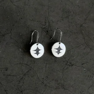 Disc Earrings in S925 Sterling Silver with engraved black starburst design and textured hooks; placed on cracked dark surface to highlight handcrafted detail, modern contrast, and artistic elegance in engraved earrings.