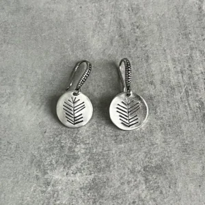 Disc Earrings in S925 Sterling Silver with engraved leaf or branch design; placed on textured gray surface to highlight minimalist elegance, handcrafted detail, and organic artistry in engraved earrings.