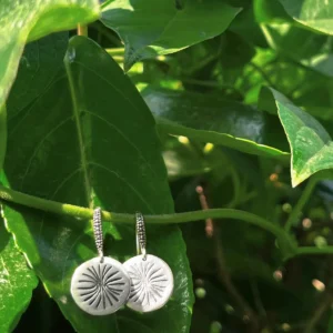 Disc Earrings in S925 Sterling Silver with engraved sunburst design; hanging from green vine among lush leaves, showcasing handcrafted detail and nature-inspired elegance in engraved earrings.