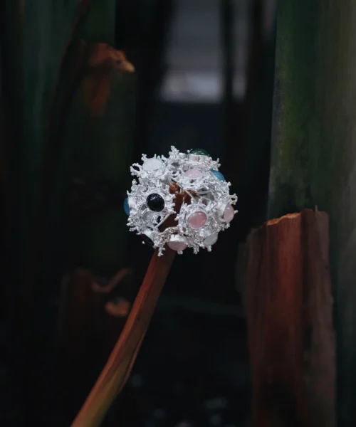 Gemstone Stud Earrings in S925 Sterling Silver with organic splash-inspired design and multicolored stones; decorative piece mounted on dried stem, styled against moody natural background to highlight contrast and craftsmanship.