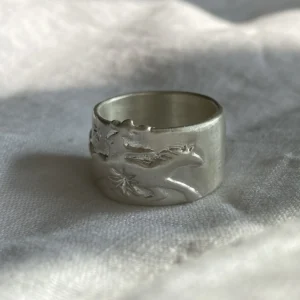 Handcrafted 999 Silver Ring with cowboy and horse motif; placed on soft fabric, featuring embossed unicorn with wings and star detail, highlighting fantasy-inspired artistry and poetic Horse Ring craftsmanship.