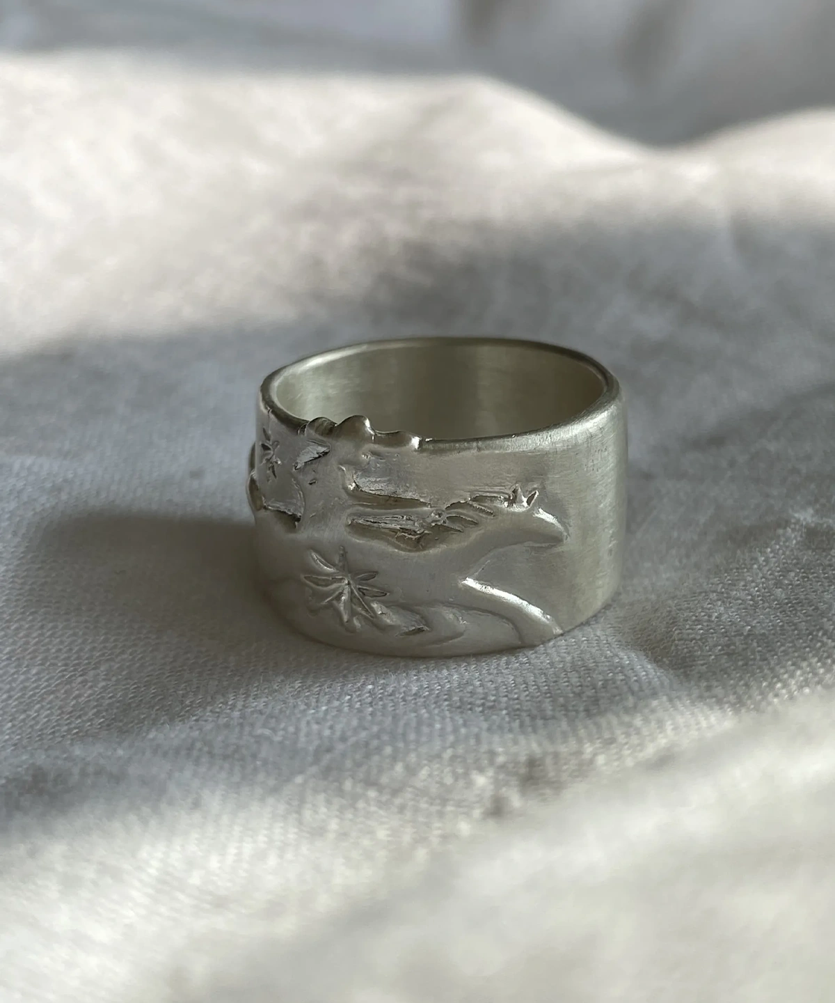 Handcrafted 999 Silver Ring with cowboy and horse motif; placed on soft fabric, featuring embossed unicorn with wings and star detail, highlighting fantasy-inspired artistry and poetic Horse Ring craftsmanship.
