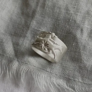 Handcrafted 999 Silver Ring with cowboy and horse motif; placed on textured fabric, featuring embossed dolphin and starfish details that evoke oceanic storytelling within a poetic Horse Ring design.