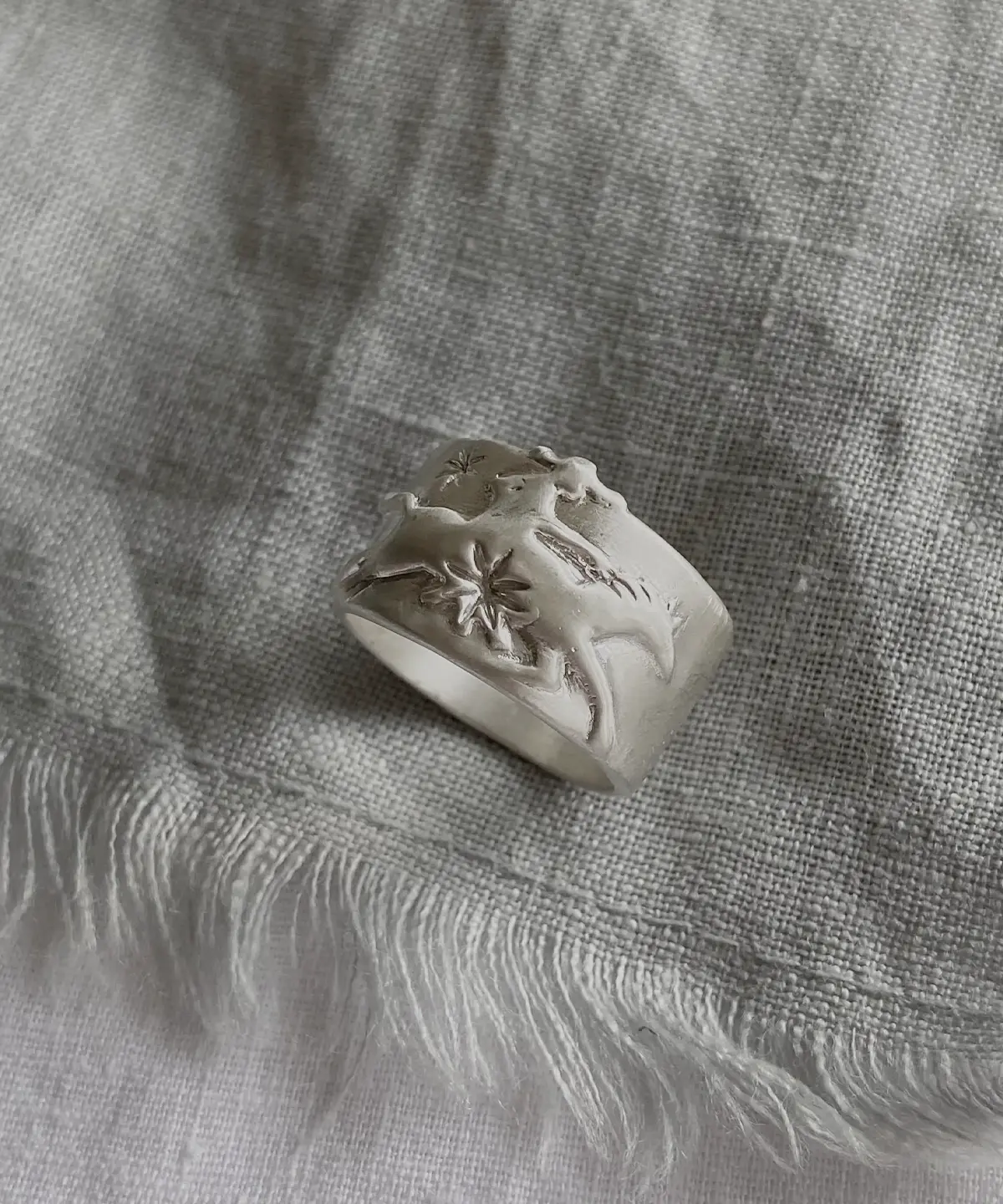 Handcrafted 999 Silver Ring with cowboy and horse motif; placed on textured fabric, featuring embossed dolphin and starfish details that evoke oceanic storytelling within a poetic Horse Ring design.