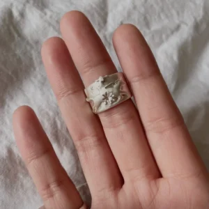 Handcrafted 999 Silver Ring with cowboy and horse motif; worn on middle finger over soft white fabric, featuring star and floral engravings that highlight poetic detail and artisan Horse Ring craftsmanship.