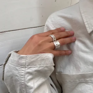 Handcrafted 999 Silver Ring with cowboy and horse motif; worn on hand resting over light shirt, styled against rustic white wood background to highlight equestrian symbolism, artisanal texture, and poetic Horse Ring design.