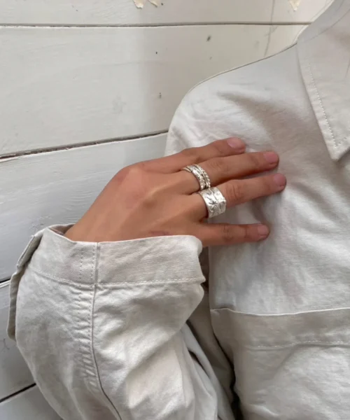 Handcrafted 999 Silver Ring with cowboy and horse motif; worn on hand resting over light shirt, styled against rustic white wood background to highlight equestrian symbolism, artisanal texture, and poetic Horse Ring design.