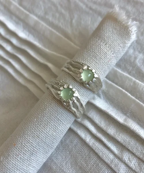 Silver Gemstone Rings with pale green prehnite set in textured 999 silver bands, placed on white fabric.