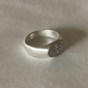 999 Silver Signet Ring with engraved organic tree design on matte circular face; handcrafted Silver Signet Ring placed on light textured surface, showcasing minimalist elegance and symbolic craftsmanship.