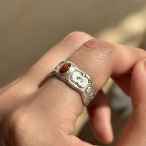 Natural Prehnite Ring in 999 Silver Green Apple Design 05 Silver ring with engraved apple motifs and a small oval red gemstone, worn on a finger and showcasing handcrafted texture.