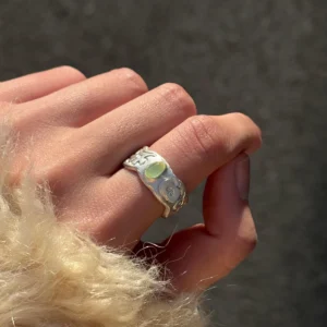Natural Prehnite Ring in 999 Silver Green Apple Design 07 Silver ring with an oval green gemstone and engraved artistic details, worn on a hand partially wrapped in soft cream fabric.