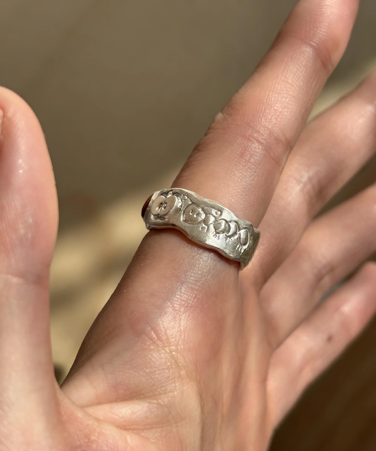 Natural Prehnite Ring in 999 Silver Green Apple Design 11 A handcrafted 999 silver band engraved with playful smiley faces and hearts, worn on the hand against soft fabric. A whimsical artisan detail styled alongside the Natural Prehnite Ring aesthetic.