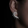 Close-up view of a left ear adorned with the Spiral Earrings | S925 Sterling Silver Designer Ear Stud. This silver earring features a striking spiral design, wrapping along the ear with its refined, pointed tips for a bold and artistic statement.