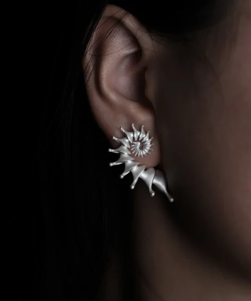Close-up view of a left ear adorned with the Spiral Earrings | S925 Sterling Silver Designer Ear Stud. This silver earring features a striking spiral design, wrapping along the ear with its refined, pointed tips for a bold and artistic statement.